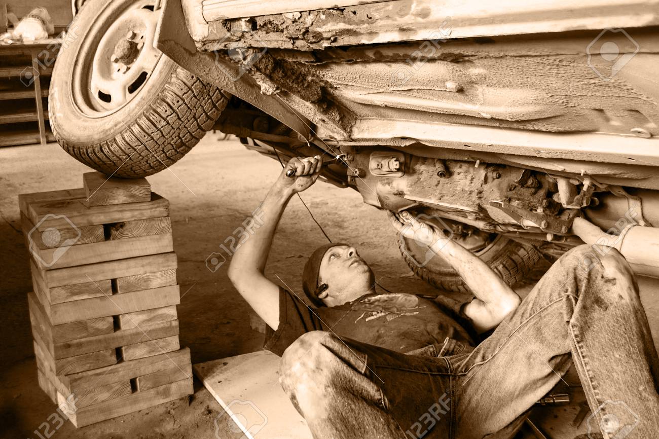 79406696-a-worker-is-repairing-an-old-car-bottom-view-black-and-white-.jpg