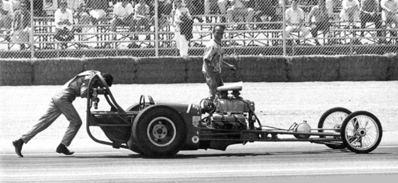 Danny Ongias pushing his Top Gas dragster (with broken axle) at Riverside, - June 1964.jpg