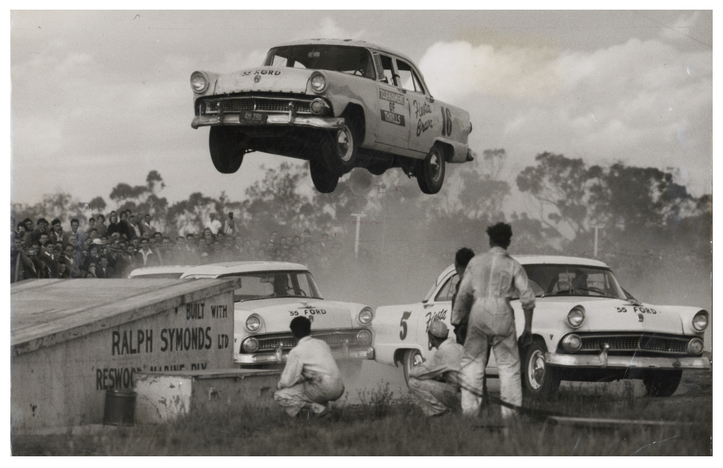 Stunt driver Don Chadwick jumping from ramp to ramp, Baxter Park Speedway, Frankston - 1955.png