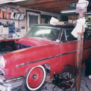 2003: Presumably this is Sonny's shop. Tight, but cozy. The suspension work appears to have already been done as the car sits nice and low, even without the engine in place. The trim had also already been removed at this point. Why? Who knows. Perhaps the plan was to weld up all the holes other than the ones for the horizontal rub strips. Mystery. Notice also that the bodywork near the rear wheels had also already been done and painted red at this point.